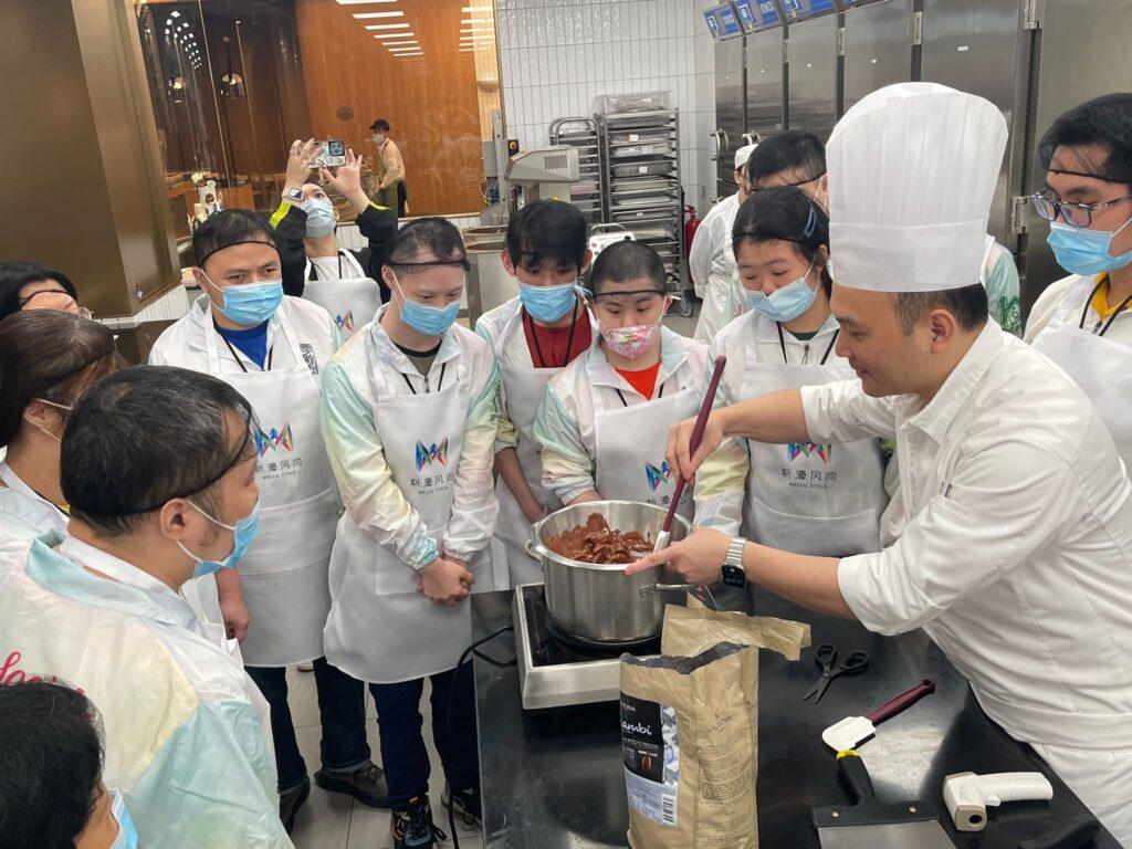 A chef in a kitchen teaching a class of students how to cook